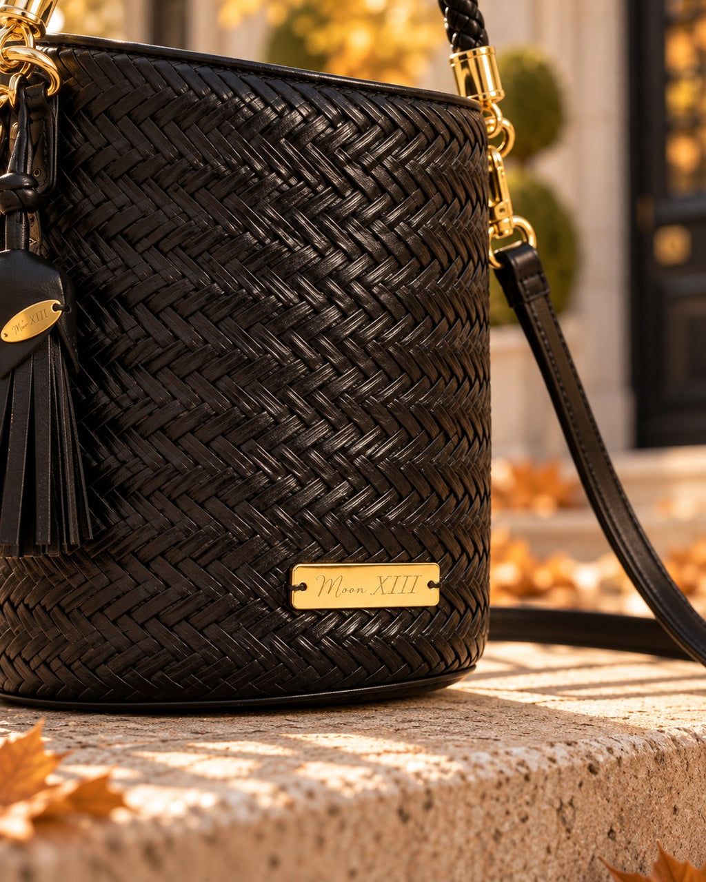 Bolso Capri Noir — detalle de la placa Moon XIII en el frente y el trenzado en espiga